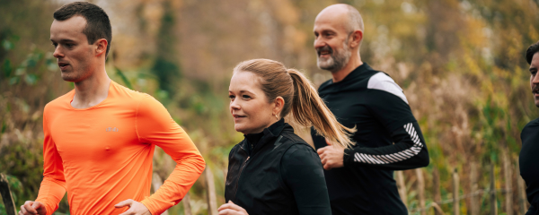 group of runners running through a lightly wooded area in autumn